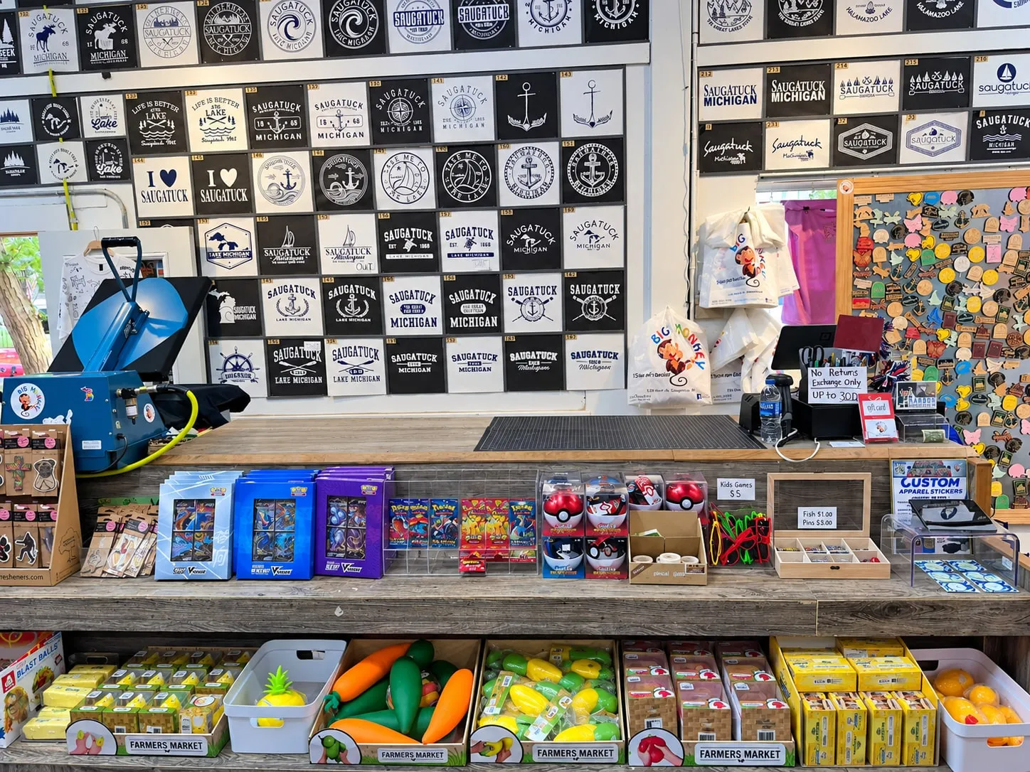 The Big Monkey counter with trading cards, toys, pins and wooden magnets, below a wall of numbered design samples