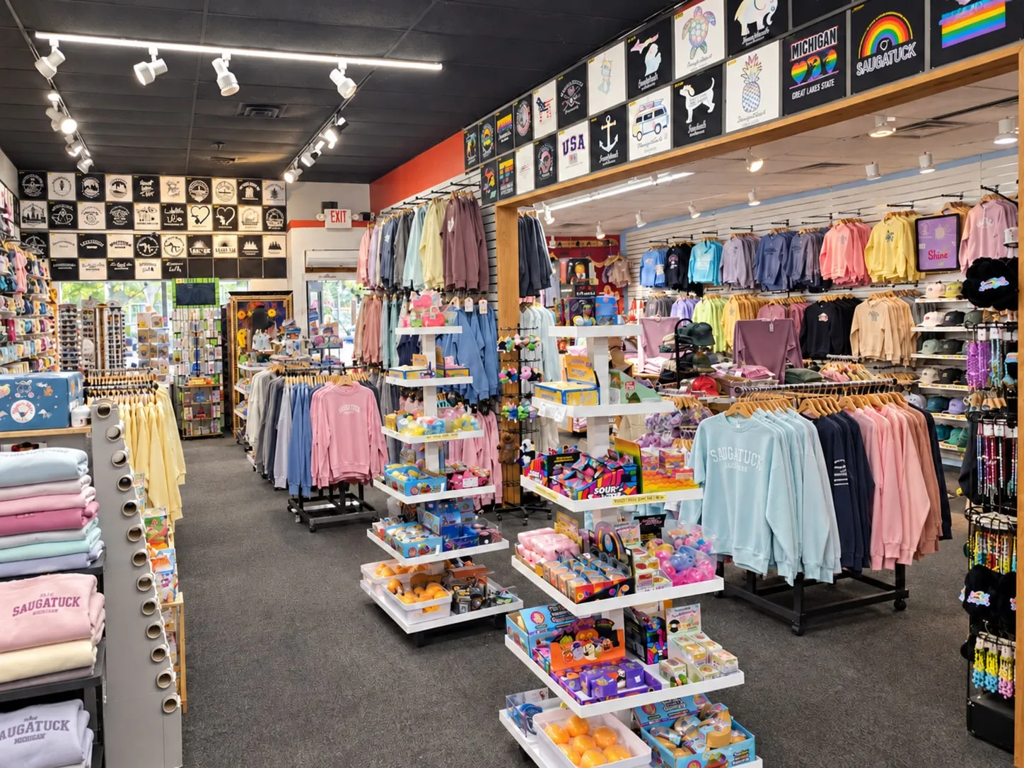 Looking down the shop aisle past racks of sweatshirts and gift shelves, with printed design samples covering the walls above